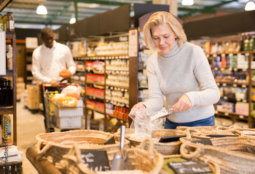 Portrait of mature blonde woman buying natural organic groats in supermarket