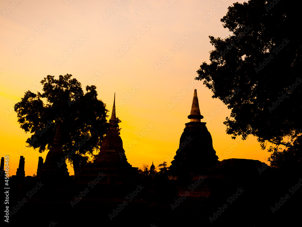 Amazing scenetic of silhouette of pagoda, temple and gold sunset sky in Sukhothai Historical Park, a UNESCO World Heritage Site in Thailand.