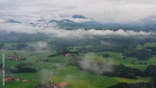 Cinematic shot , aerial view above clouds of mountains and green meadow in Bavaria, Germany, Europe. Autumn photo