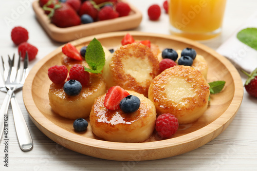 Delicious cottage cheese pancakes with fresh berries and honey on white wooden table