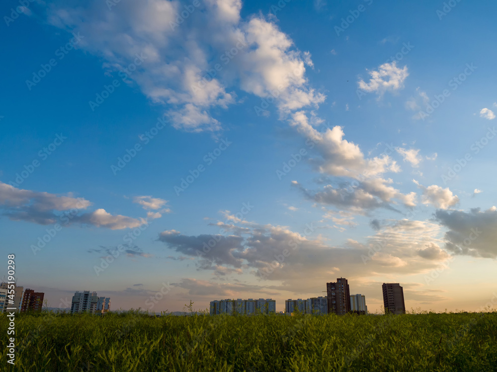 Beautiful clouds in the sky. Summer evening. Residential buildings on the horizon. Sunset landscape