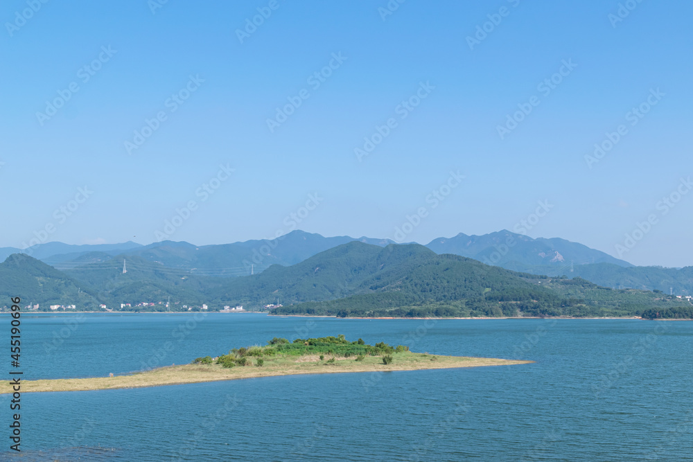 Obraz premium Blue sky, green mountains and trees surround the lake