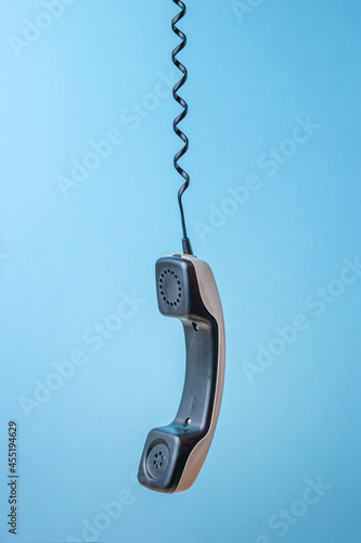 Canvas Print A gray retro phone handset suspended from a wire on a blue background
