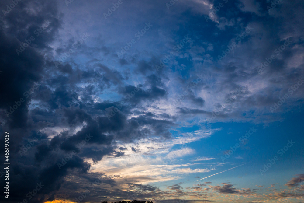 Obraz premium 夏の終わりの夕暮れの西日と青空と暗い雲
