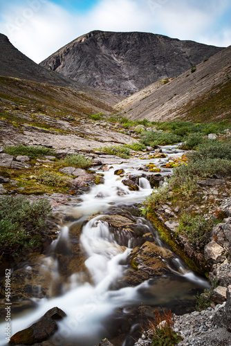 Beautiful landscape of the Khibiny mountains with rocks and a mountain stream on a summer day. Kola Peninsula, Russia. Long exposure