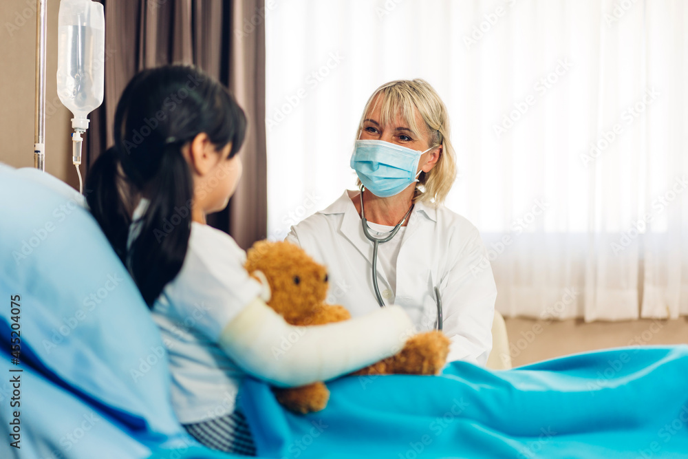 Woman senior doctor service help support discussing and consulting talk to little girl patient give teddy bear and check up information in hospital Woman senior doctor service help support discussing and consulting talk to little girl patient give teddy bear and check up information in hospital