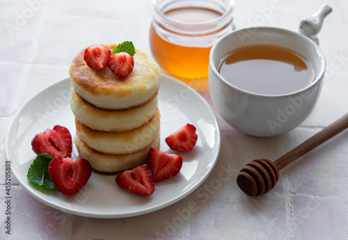 Cottage cheese pancakes, ricotta fritters on ceramic plate with fresh strawberry.