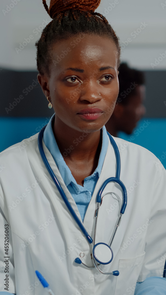 Close up of african american doctor doing consultation with senior patient sitting at desk in medical office. Black medic with white coat giving professional advice to elder man Close up of african american doctor doing consultation with senior patient sitting at desk in medical office. Black medic with white coat giving professional advice to elder man