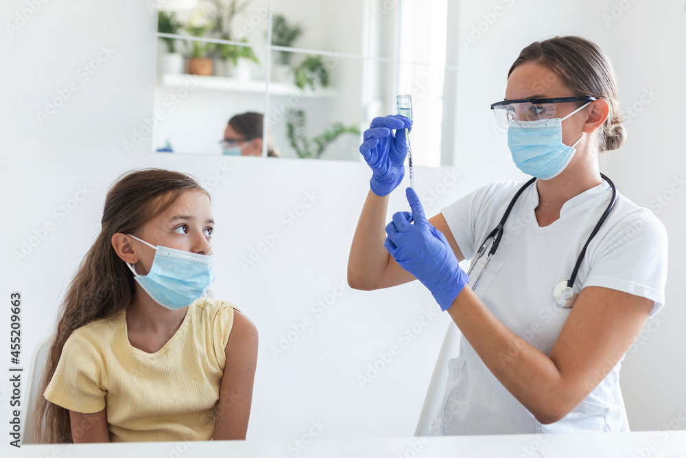 Antiviral immunization campaign concept.Doctor vaccinating girl. Girl in medical masks getting vaccinated against covid-19, doctor giving injection of coronavirus vaccine at hospital. Antiviral immunization campaign concept.Doctor vaccinating girl. Girl in medical masks getting vaccinated against covid-19, doctor giving injection of coronavirus vaccine at hospital.