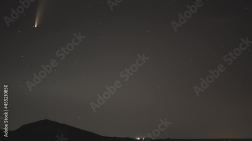 comet movement in the night sky among stars and meteors over the village in the mountains photo