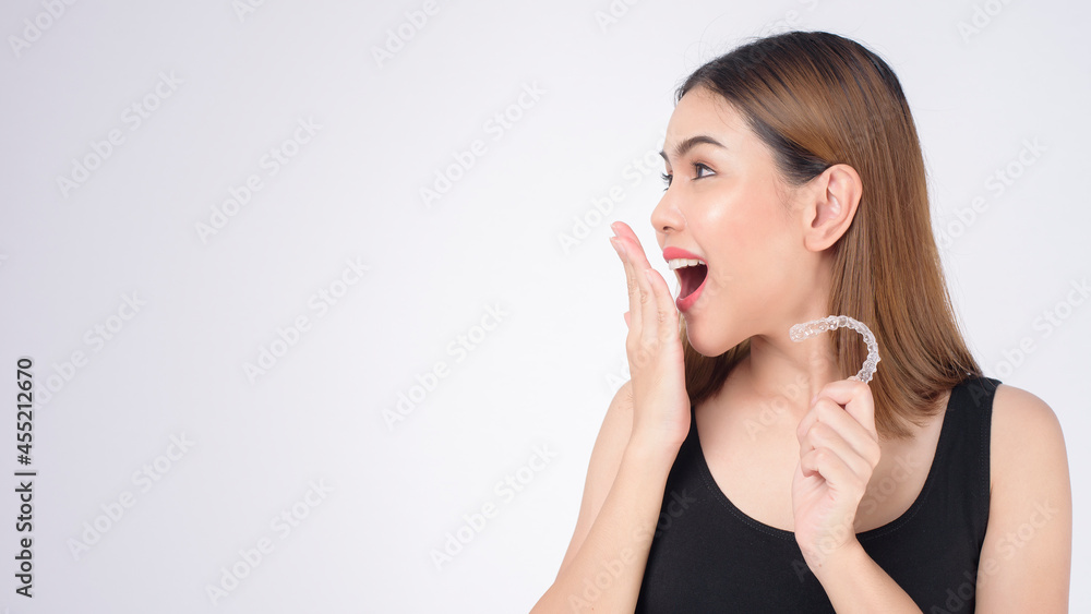 Young smiling woman holding invisalign braces in studio, dental healthcare and Orthodontic concept Young smiling woman holding invisalign braces in studio, dental healthcare and Orthodontic concept