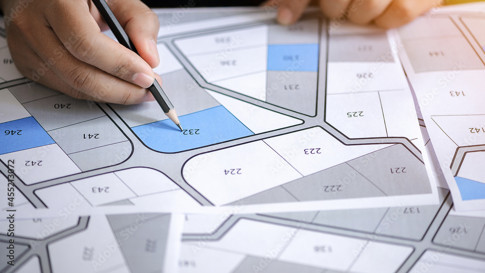 hand hold pencil to point on the cadastral map - choose and buy a building plot for house construction hand hold pencil to point on the cadastral map - choose and buy a building plot for house construction