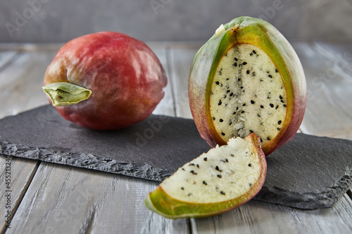 Peruvian apple cactus fruits whole and cut on wooden stand on gray board. Scientific name Cereus repandus photo