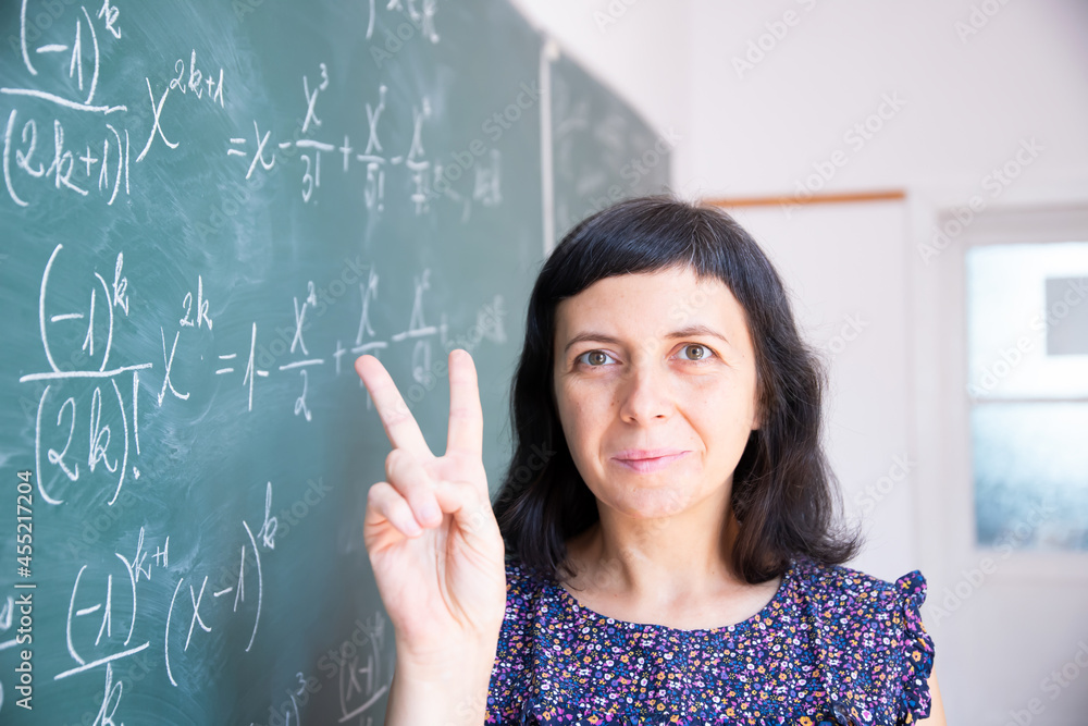 Female student or teacher in the classroom writing on chalkboard mathematical equations Female student or teacher in the classroom writing on chalkboard mathematical equations