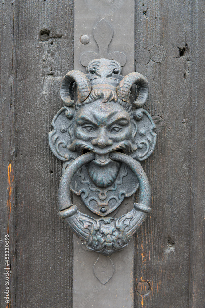 scary door knocker as a devil on an old wooden door