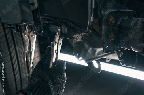 Wall Mural Professional repairman placing locking pliers under the car