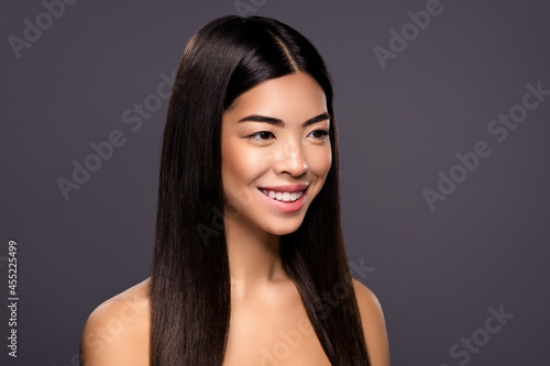 Photo of positive peaceful serene chinese brunette lady look empty space beaming smile isolated grey color background
