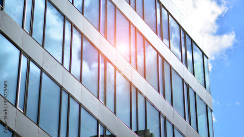 Facade texture of a glass mirrored office building. Fragment of the facade. Bottom view of modern skyscrapers in business district in evening light at sunset with lens flare filter effect.