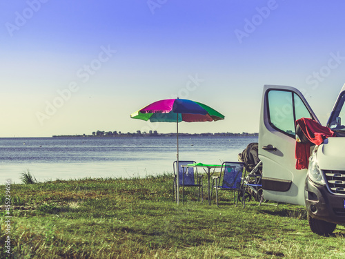 Umbrella with chairs at campervan on beach