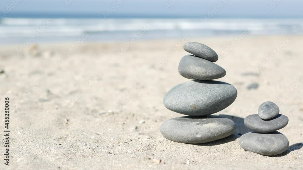 Rock balancing on ocean beach, stones stacking by sea water waves. Pyramid of pebbles on sandy shore. Stable pile or heap in soft focus with bokeh, close up. Zen balance, minimalism, harmony and peace Rock balancing on ocean beach, stones stacking by sea water waves. Pyramid of pebbles on sandy shore. Stable pile or heap in soft focus with bokeh, close up. Zen balance, minimalism, harmony and peace