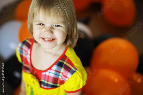 Portrait of a small child lying on the floor in a room decorated with balloons. Happy childhood concept.