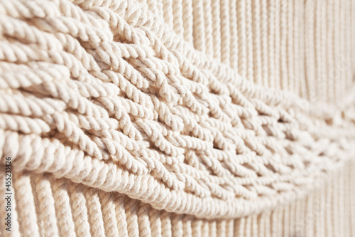 Close-up of hand made macrame texture pattern. ECO friendly modern knitting DIY natural decoration concept in the interior. Handmade macrame 100% cotton. Female hobby.