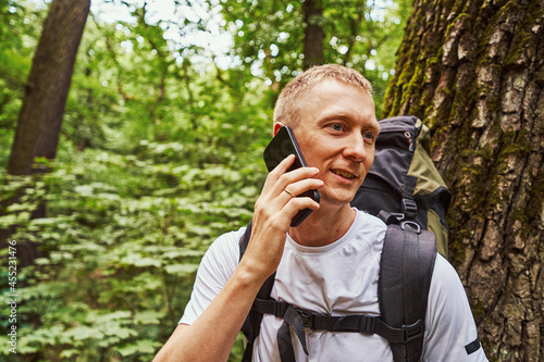 Cheerful young man making call in forest
