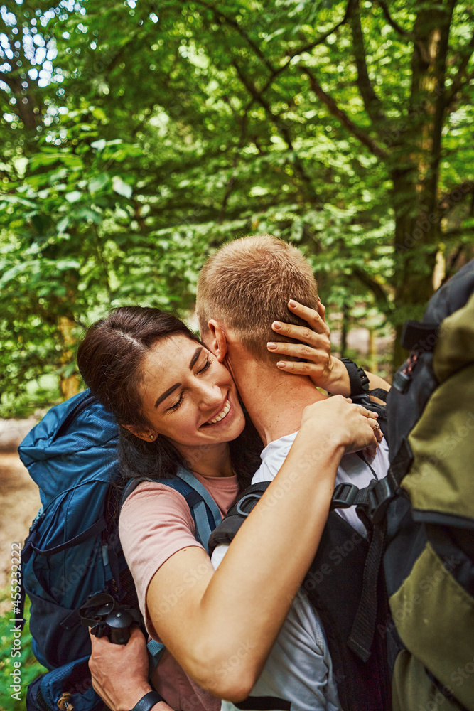 Happy couple with backpacks hugging in nature Happy couple with backpacks hugging in nature