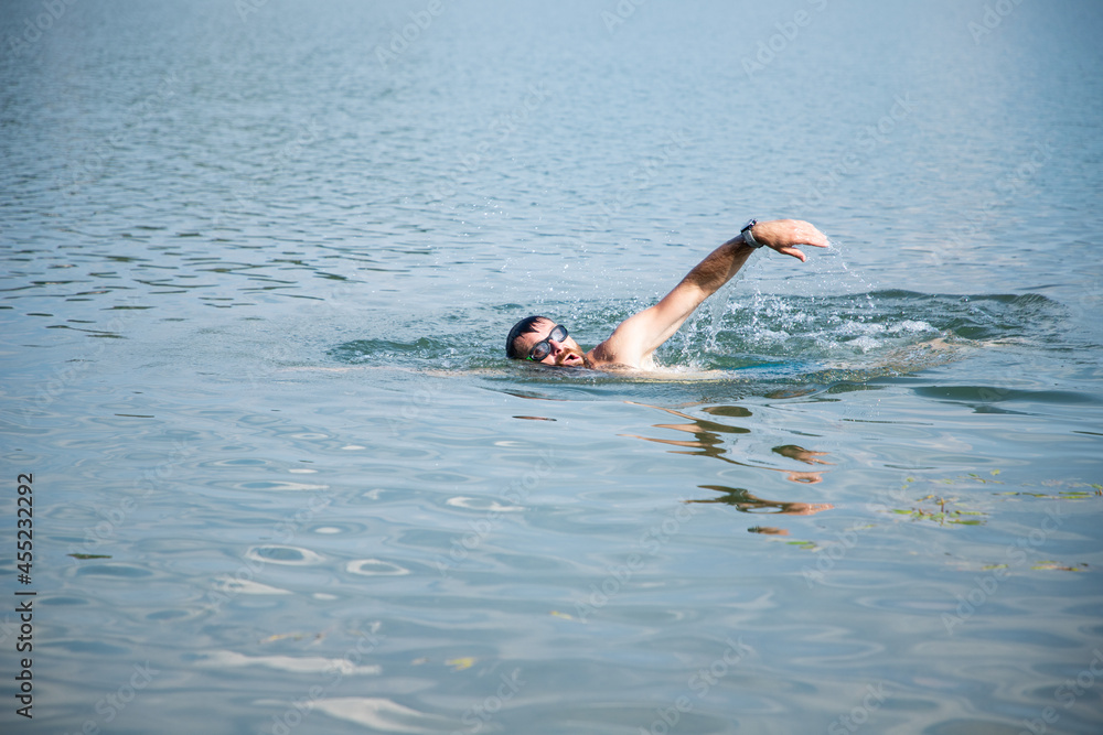 man swimming in open water lake
