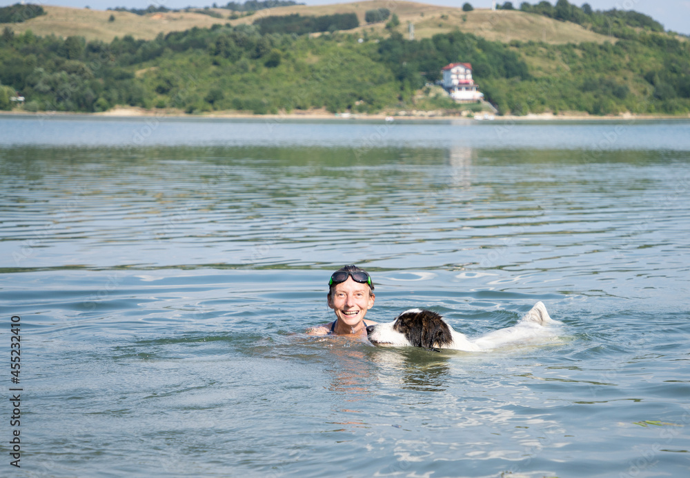 woman and dog swimming in lake
