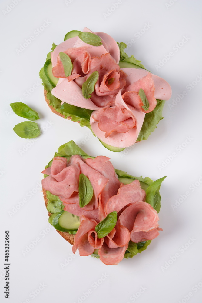Open ham Sandwich with cucumbers, basil, and a crusty slice of rye bread and salami Open ham Sandwich with cucumbers, basil, and a crusty slice of rye bread and salami