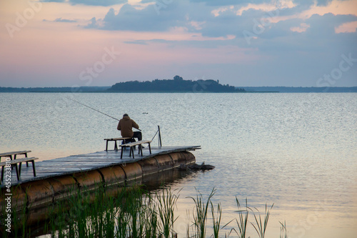 A fisherman on the pier is fishing. Morning fishing