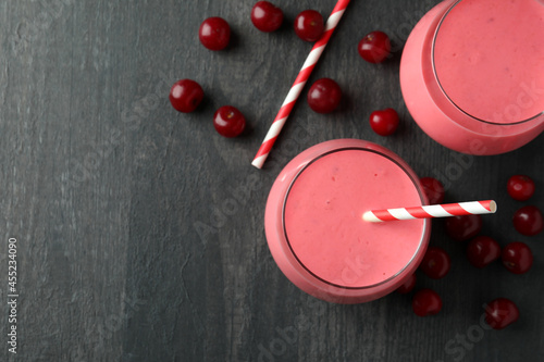 Glasses of cherry smoothie and ingredients on dark wooden table