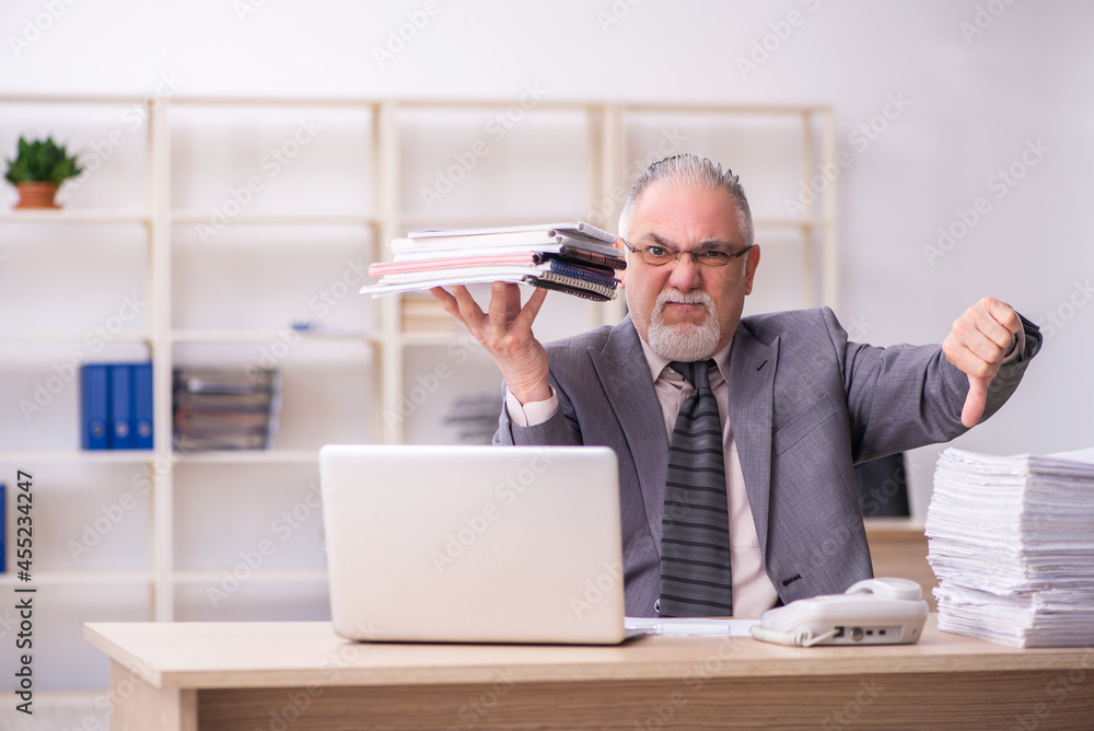 Old male employee working at workplace Old male employee working at workplace