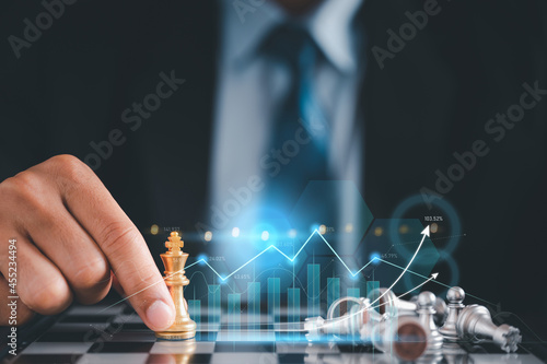 Businessman in black suite sitting player chess.meaning of planning and strategy ecision achievement goal concept of business.