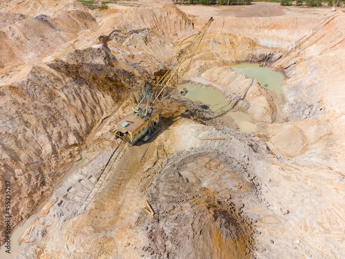 Boom walking excavator digs ilmenite ore in quarry  aerial view