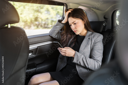 stressed business woman using a smartphone while sitting in the back seat of car © geargodz