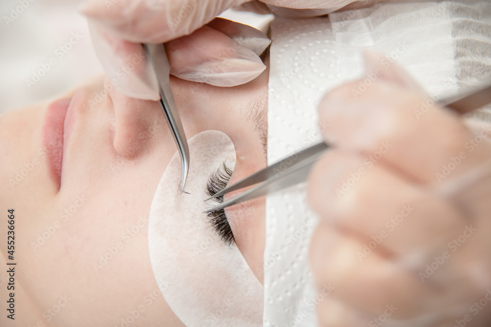 Eyelash extension procedure at beauty salon. Woman eye with long eyelashes Eyelash extension procedure at beauty salon. Woman eye with long eyelashes
