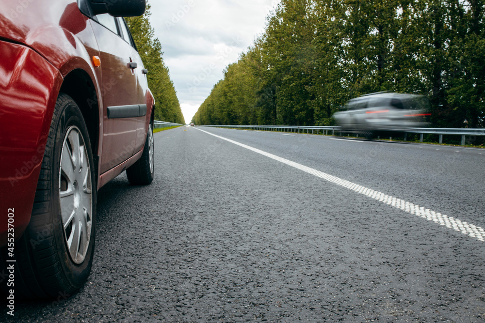 Fototapeta premium Red car on road background nature green trees