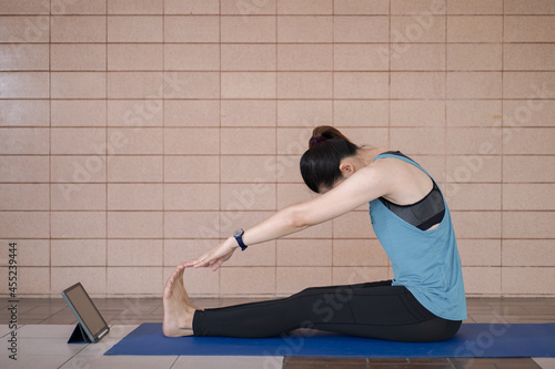 Asian woman in sports outfits worksout following online training program via digital tablet at home photo