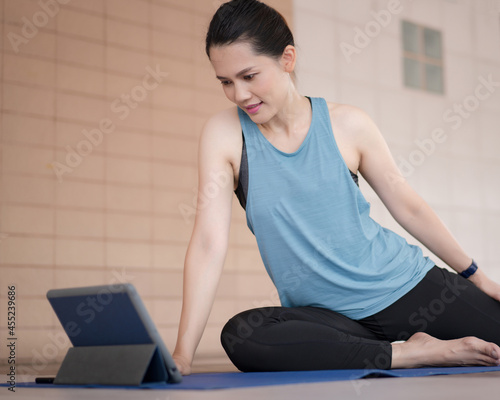 Asian woman in sports outfits worksout following online training program via digital tablet at home photo