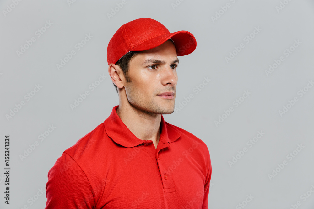 Young delivery man wearing uniform posing and looking aside