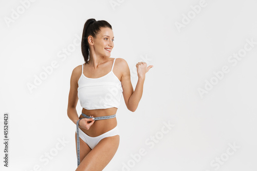 Woman wearing underwear pointing finger aside and measuring her waist