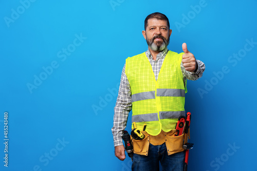 Portrait of senior construction worker in yellow vest in studio