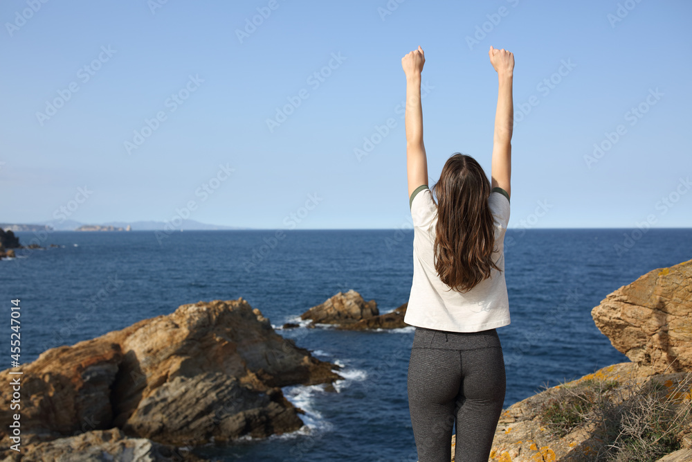 Excited woman raising arms in the coast