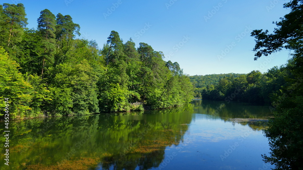 Fototapeta premium malerischer Bärensee bei Stuttgart umgeben von Laubwald und Kiefern, die sich im Wasser spiegeln