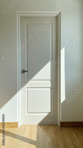 Closeup detail of white door with shadow.
