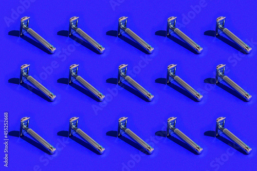 A pattern of dangerous razors. Shaving tool on a blue background with hard shadows.