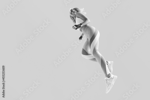 Fit young woman jumping and running looking back. Motivation fitness black and white concept photo