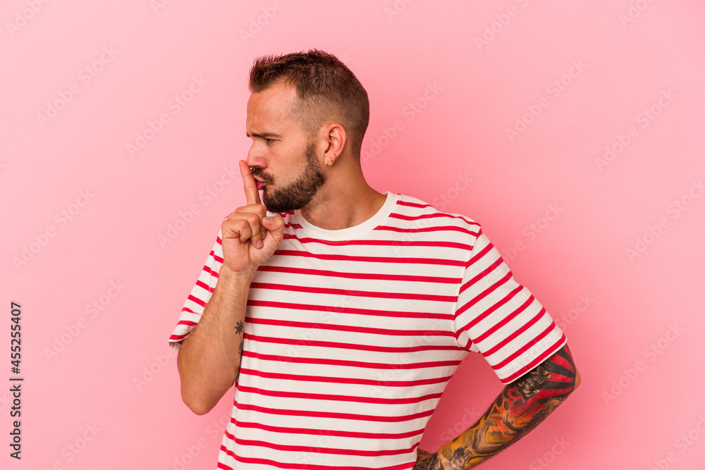 Young caucasian man with tattoos isolated on pink background keeping a secret or asking for silence. Young caucasian man with tattoos isolated on pink background keeping a secret or asking for silence.